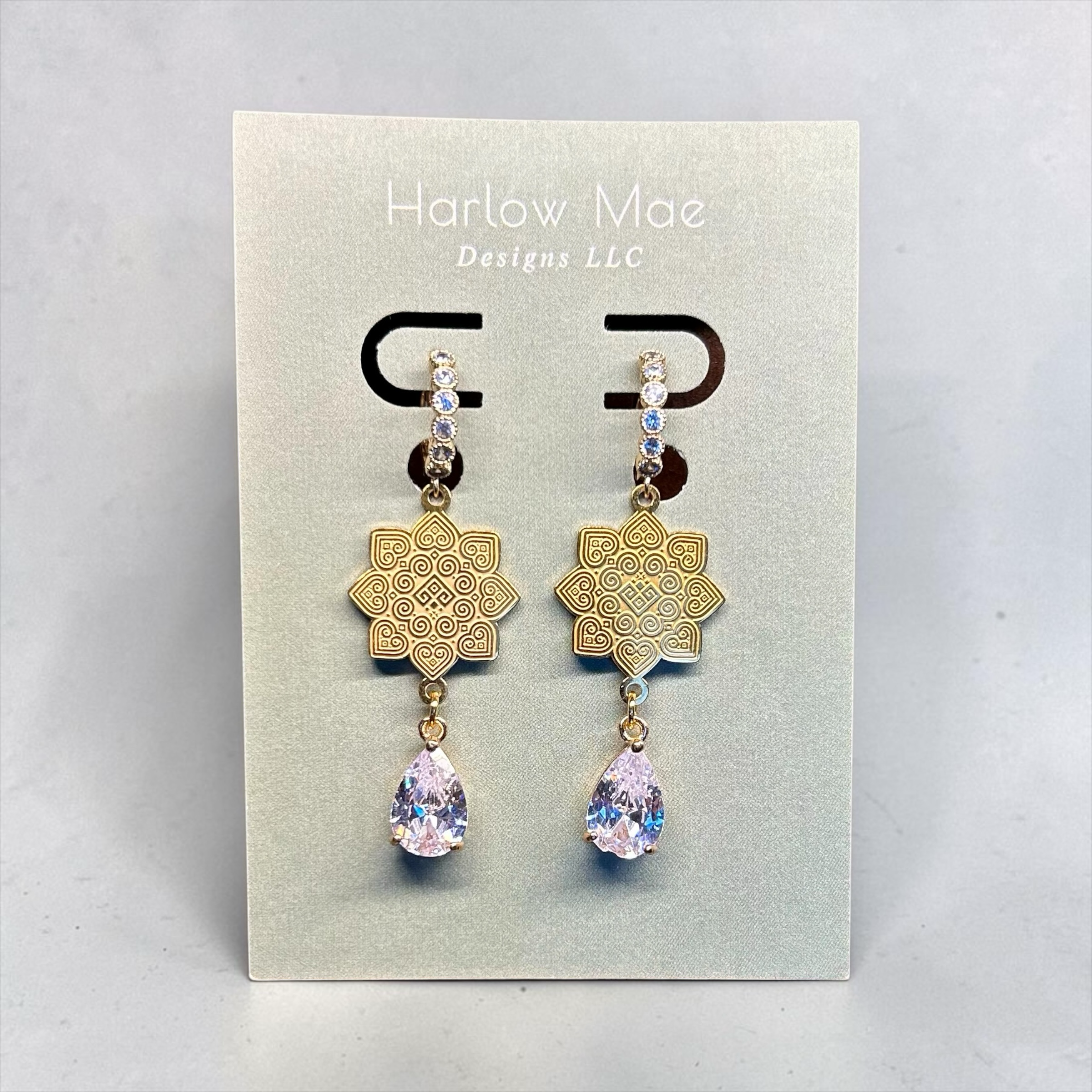Harlow Mae Designs LLC gold-tone drop earrings with star floral motif and pear-shaped cubic zirconia gemstone.