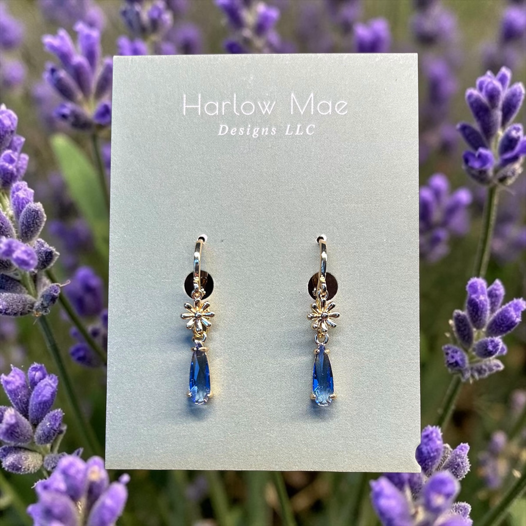 Harlow Mae delicate gold-tone star flower drop earrings with faceted blue gemstone accents.