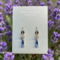 Harlow Mae delicate gold-tone star flower drop earrings with faceted blue gemstone accents.