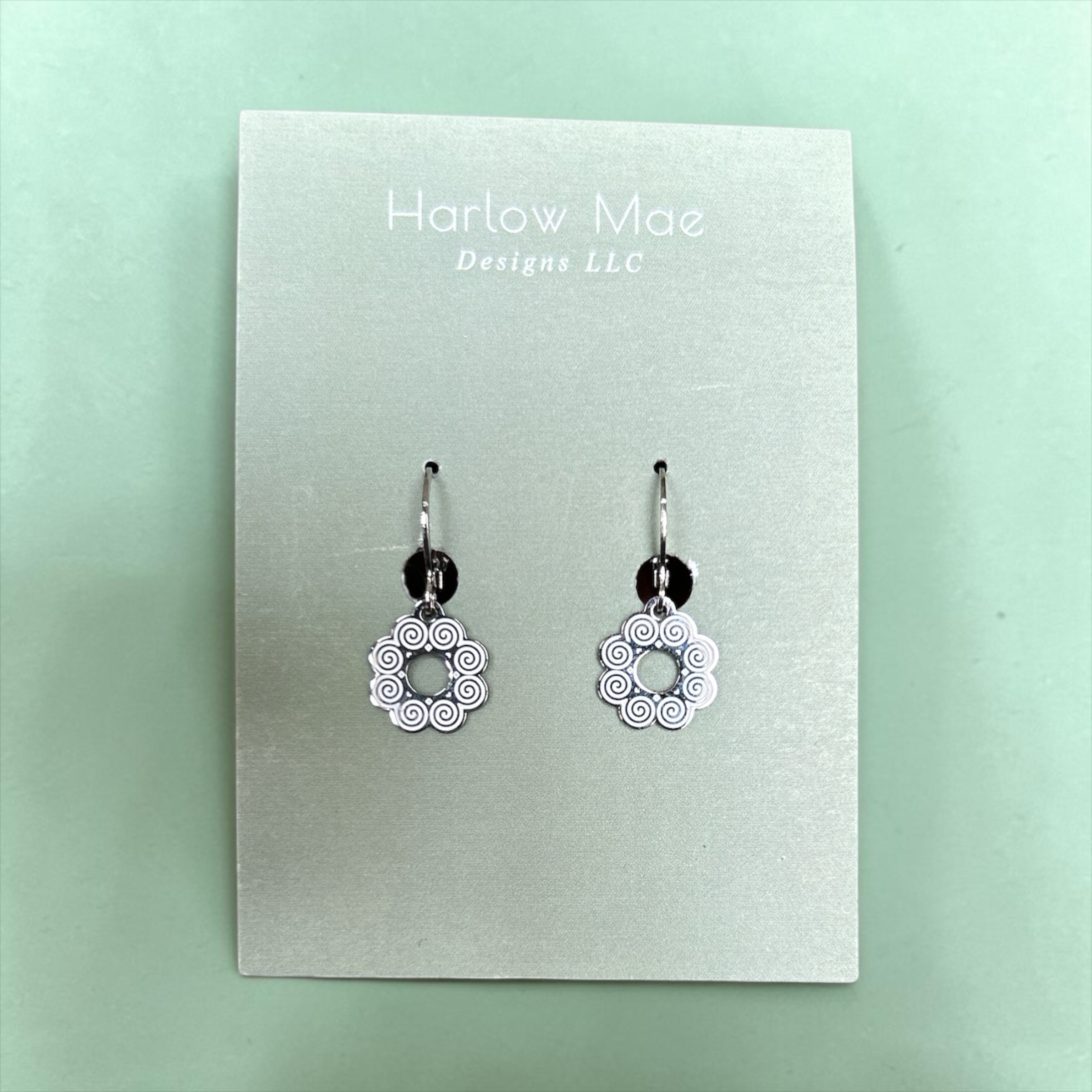 Harlow Mae silver-tone dangle earrings with swirling flower design and dark bead accent.
